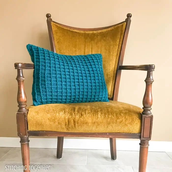 blue crochet pillow sitting on a yellow chair