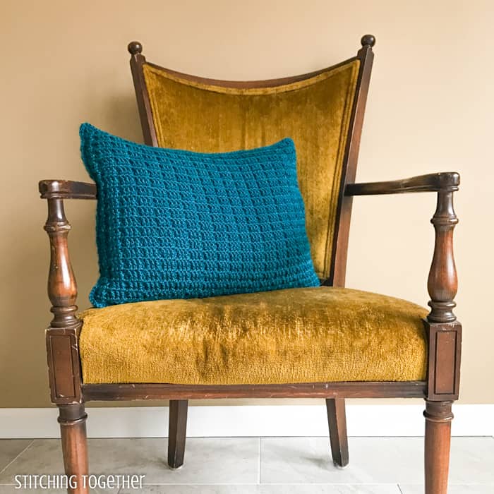 blue crochet pillow sitting on a yellow chair