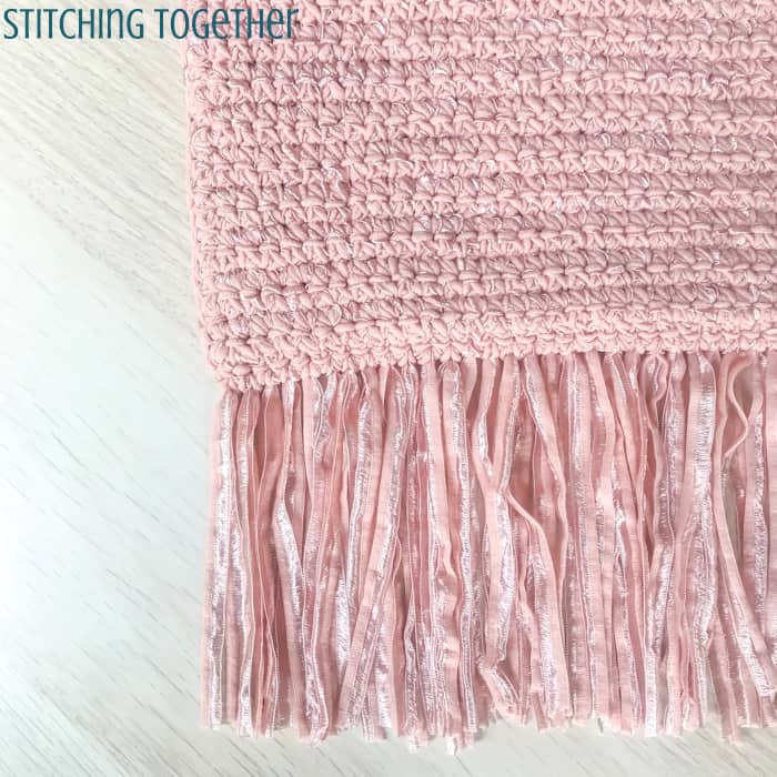 fringe of pink yarn on crochet piece