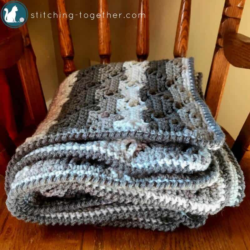 crochet baby blanket folded on a rocking chair