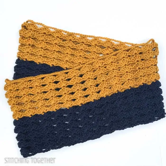 a folded color block crochet infinity scarf in gold and blue with shell stitches