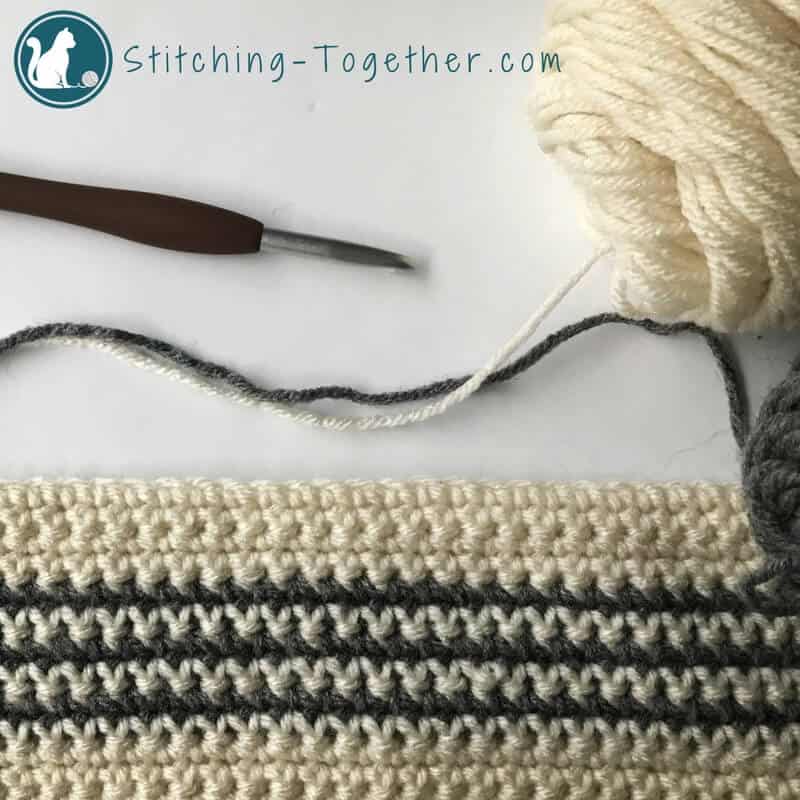 gray and off white crochet stripes in process with crochet hook