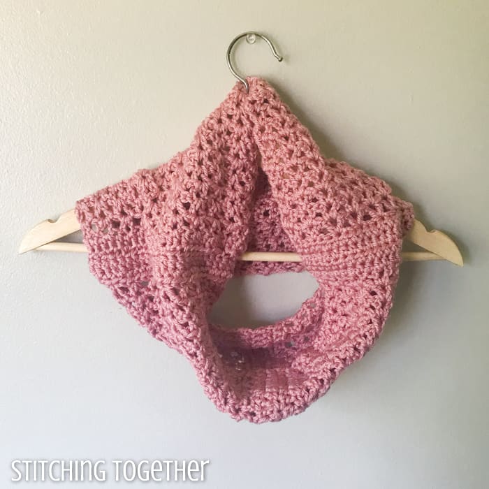 pink crochet cowl neck scarf hanging on a hanger