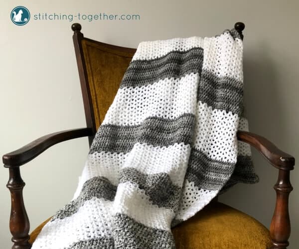 White and gray striped v stitch crochet blanket on chair