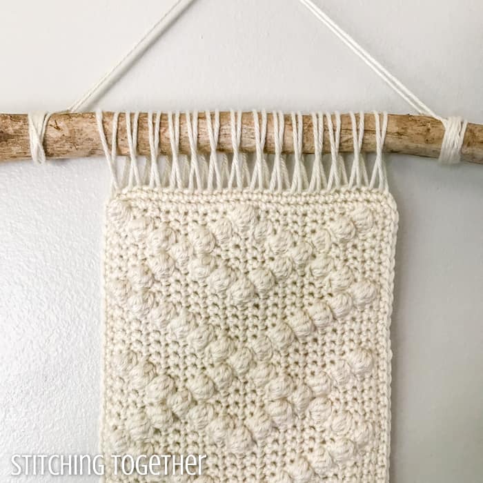 close up of neutral crochet wall hanging with bobbles