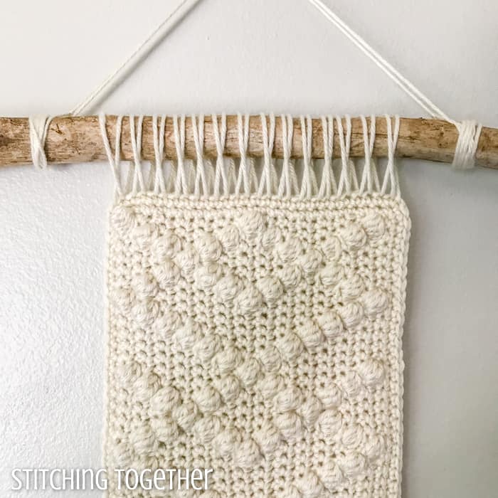 close up of neutral crochet wall hanging with bobbles