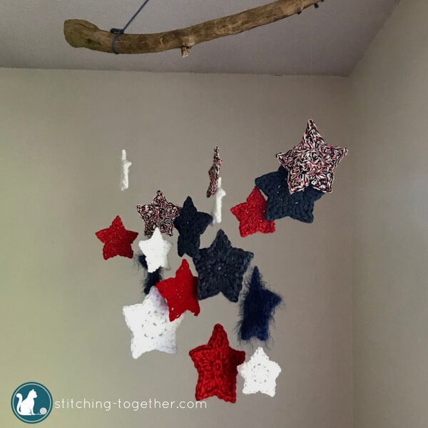 DIY this adorable crochet stars wall hanging! Using scrap yarn stars, invisible thread, and a tree branch, you can create this perfect holiday decoration. Make it red, white and blue for the 4th of July or red and green for Christmas. The possibilities ae endless with this fun and quick weekend project.