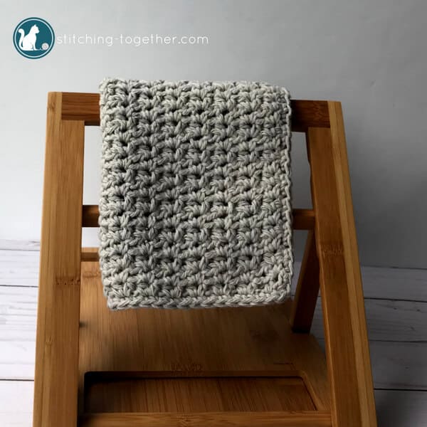 gray crochet washcloth hanging on bamboo rack