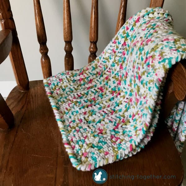 crib blanket on small chair with colors for a girl