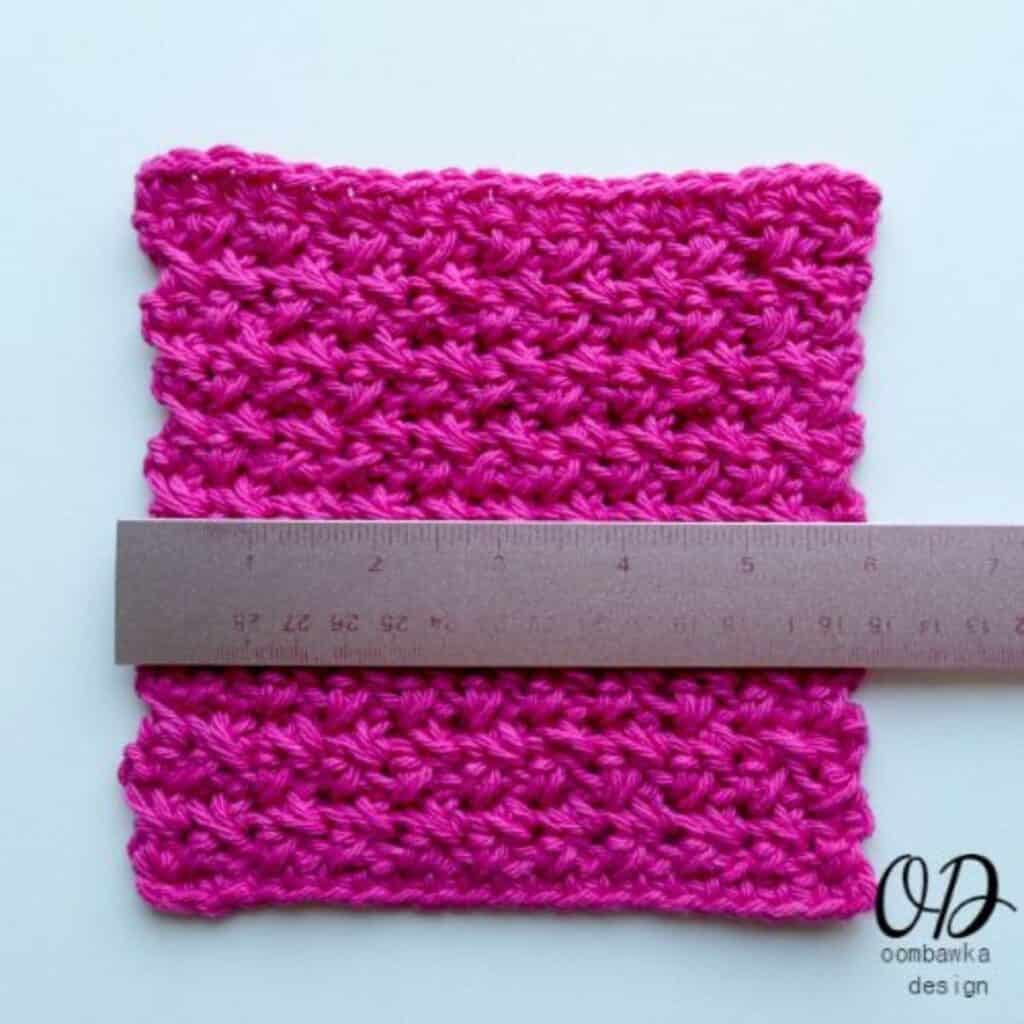 bright pink textured crochet dishcloth with a ruler laying across the top