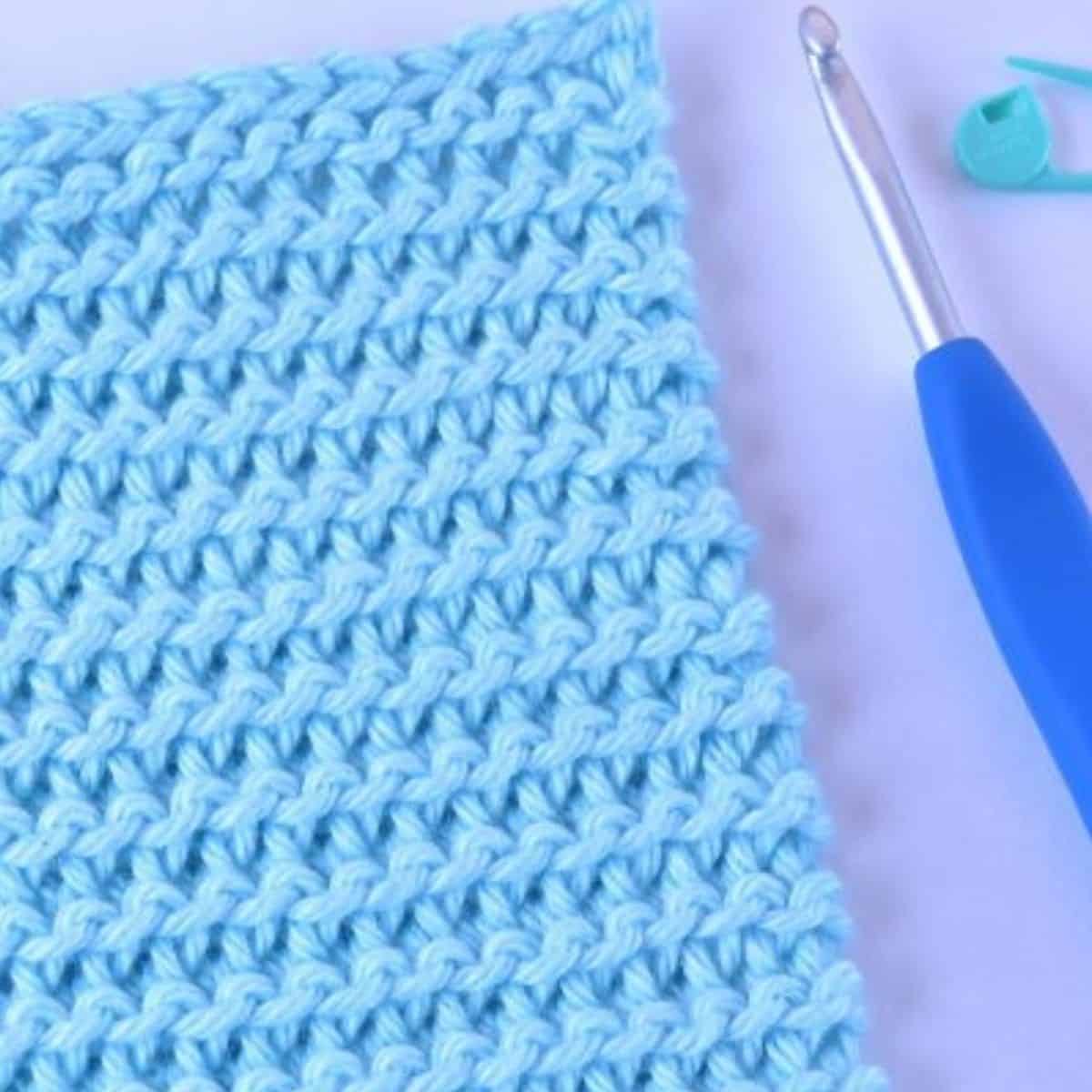 close up of blue crochet garter stitches and a crochet hook