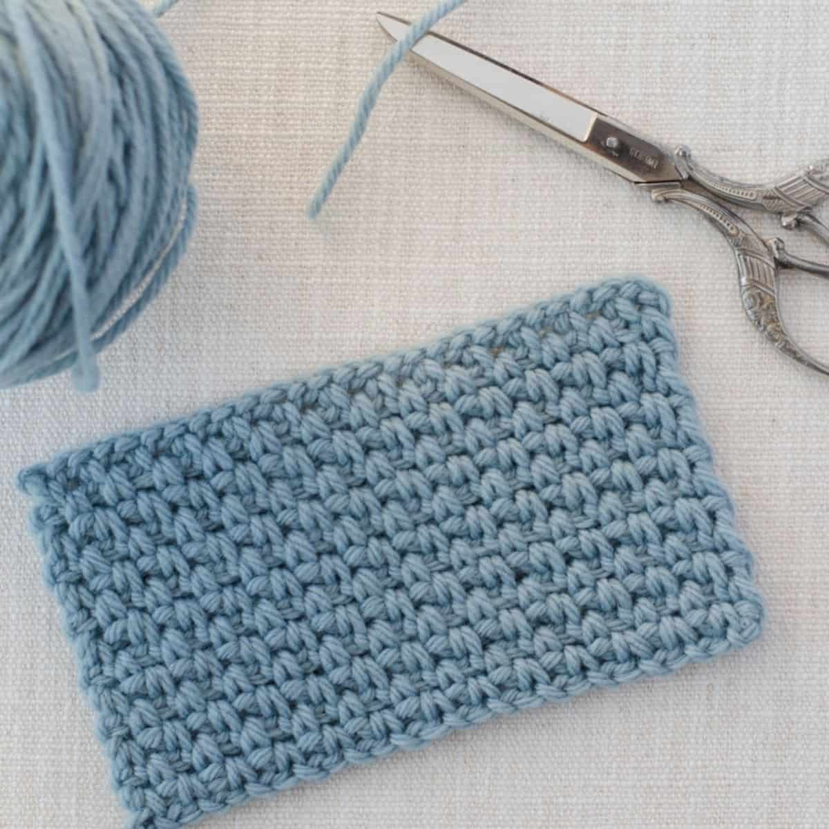 swatch of the linen crochet stitch next to yarn and a pair of scissors