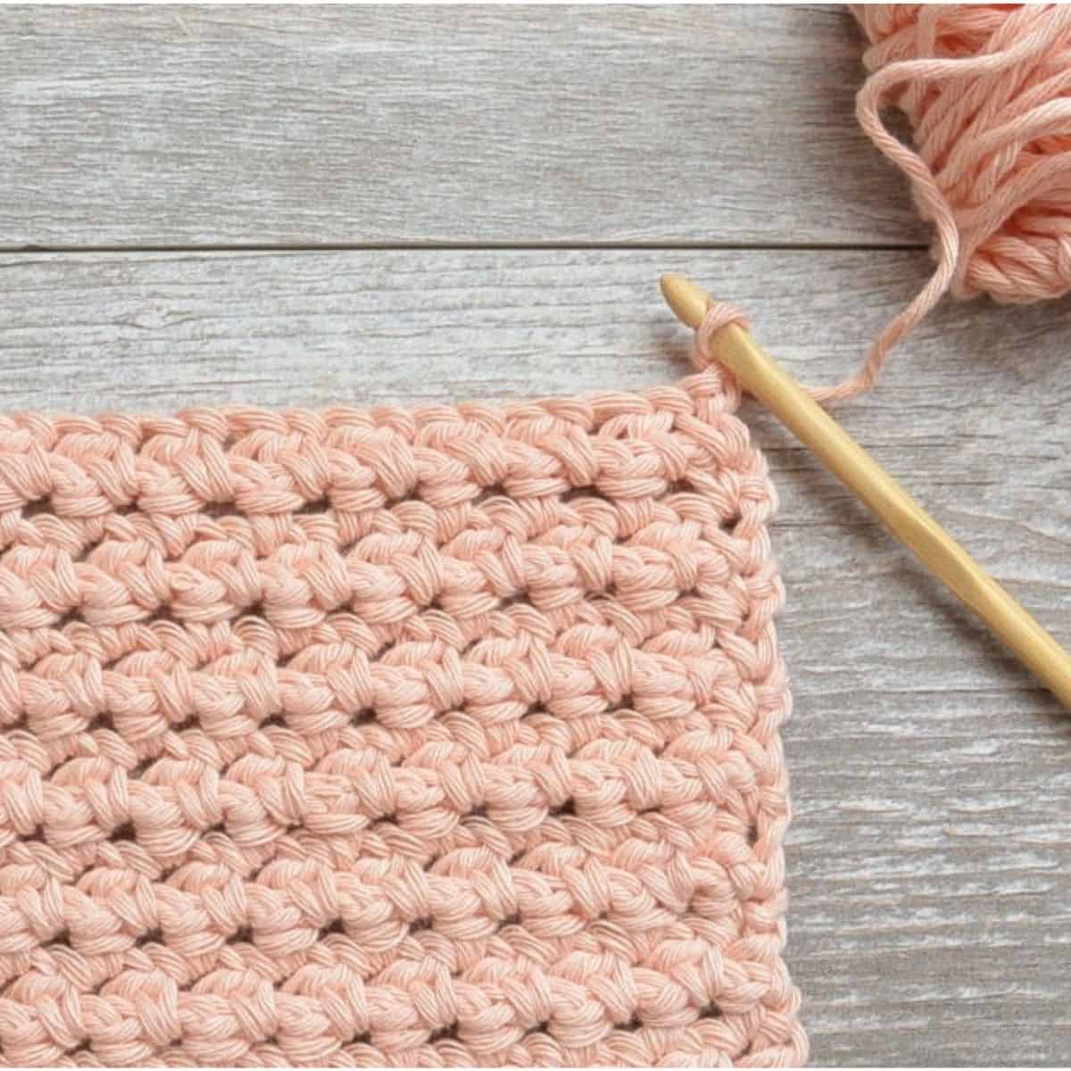 soft pink crochet stitch swatch with hook and yarn