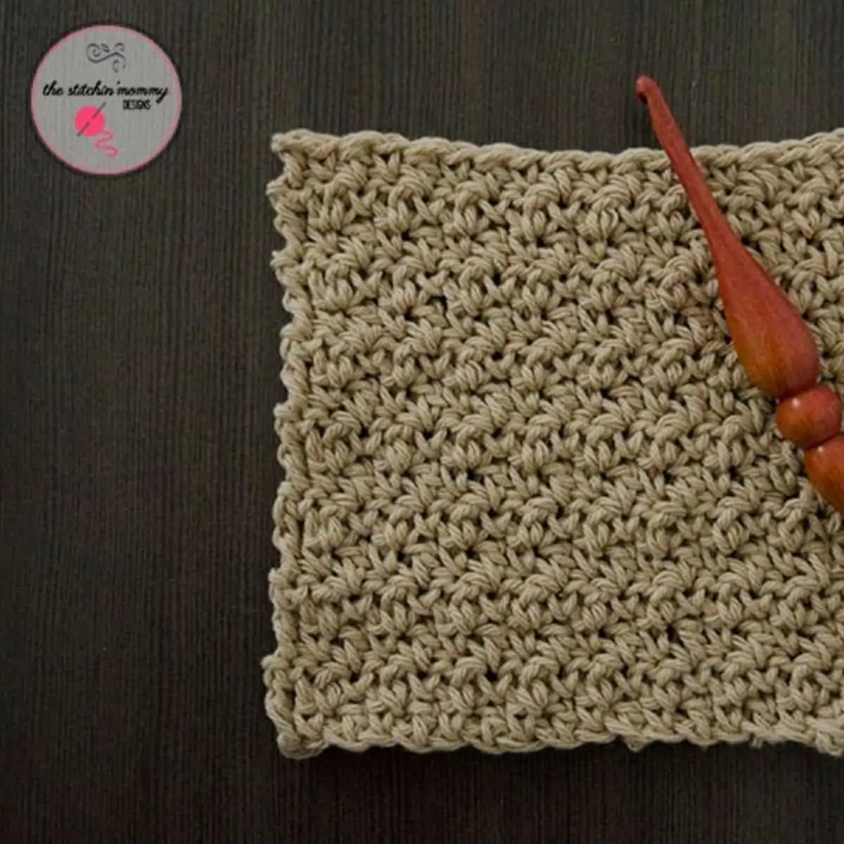square seed stitch washcloth with a wooden crochet hook laying on top