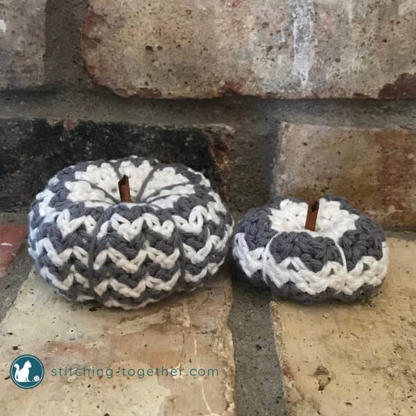 crochet pumpkins, gray and white, on brick