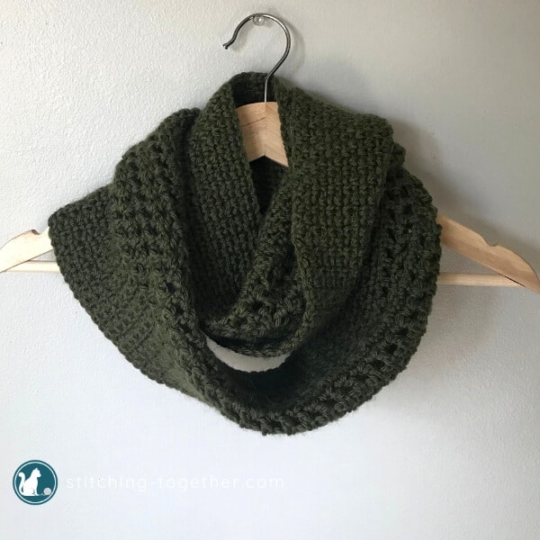 green crochet infinity scarf wrapped on a hanger