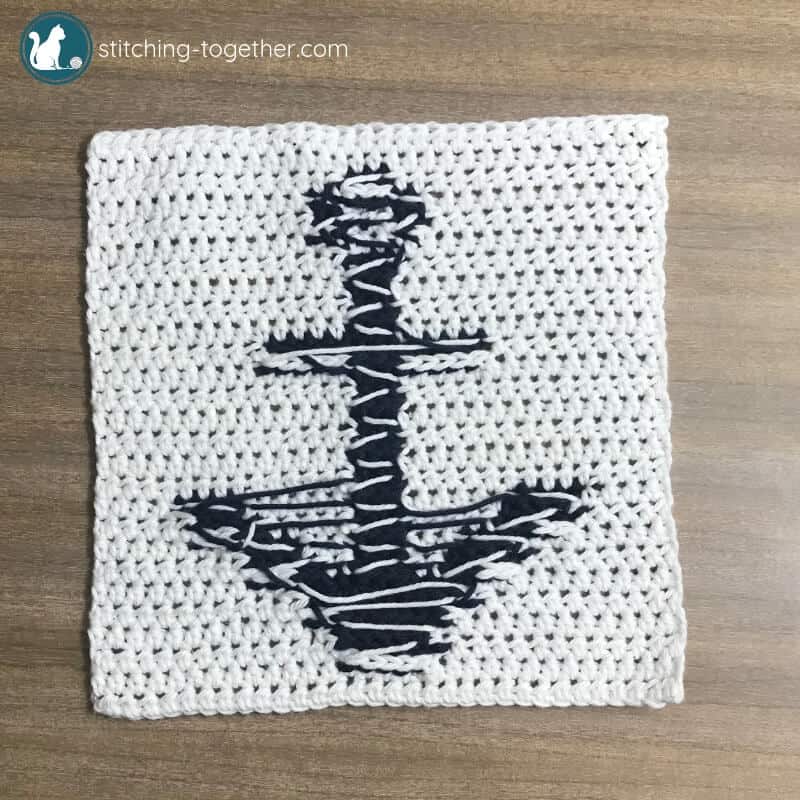 backside of a white crochet square with a blue anchor