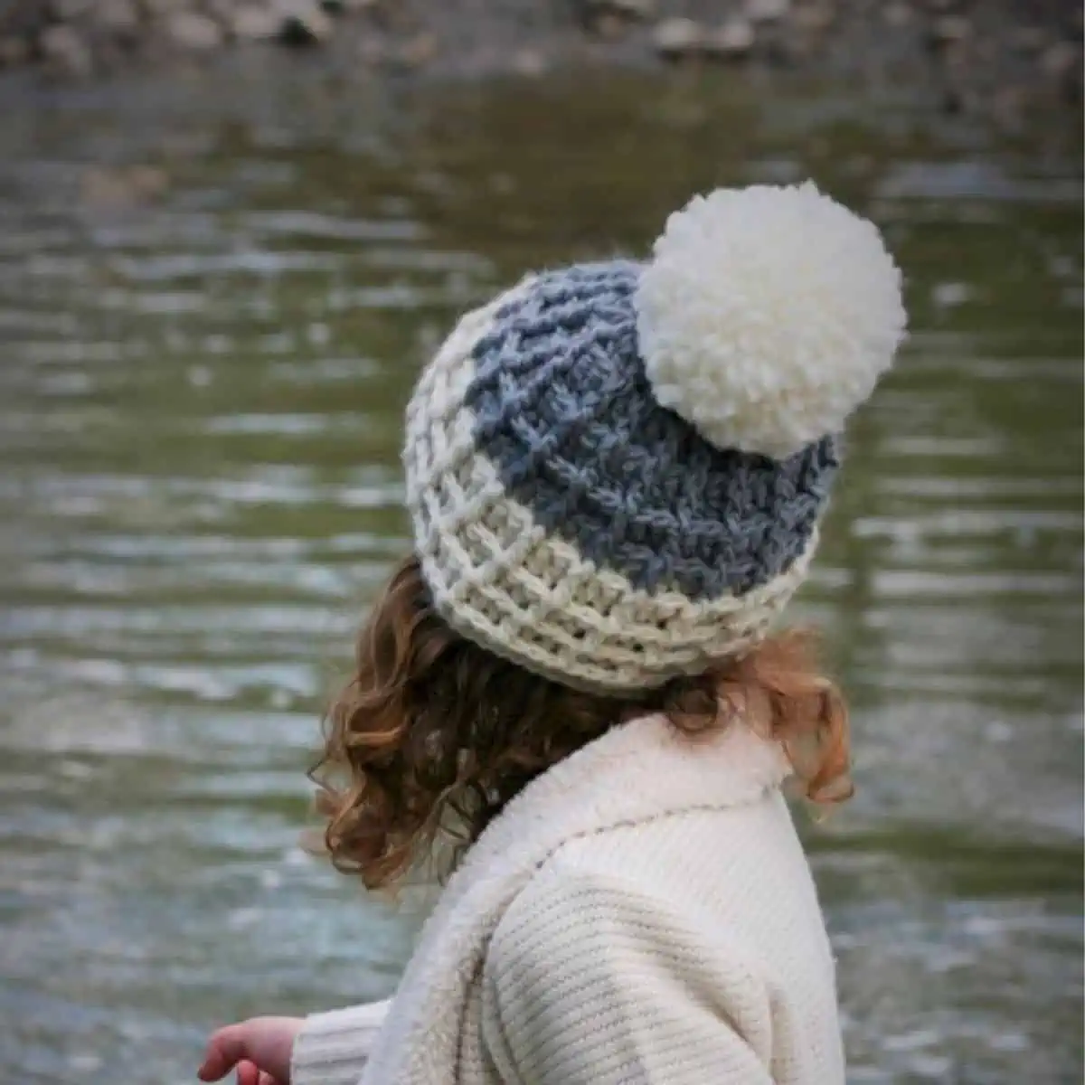 person wearing a crochet hat with a large pom pom