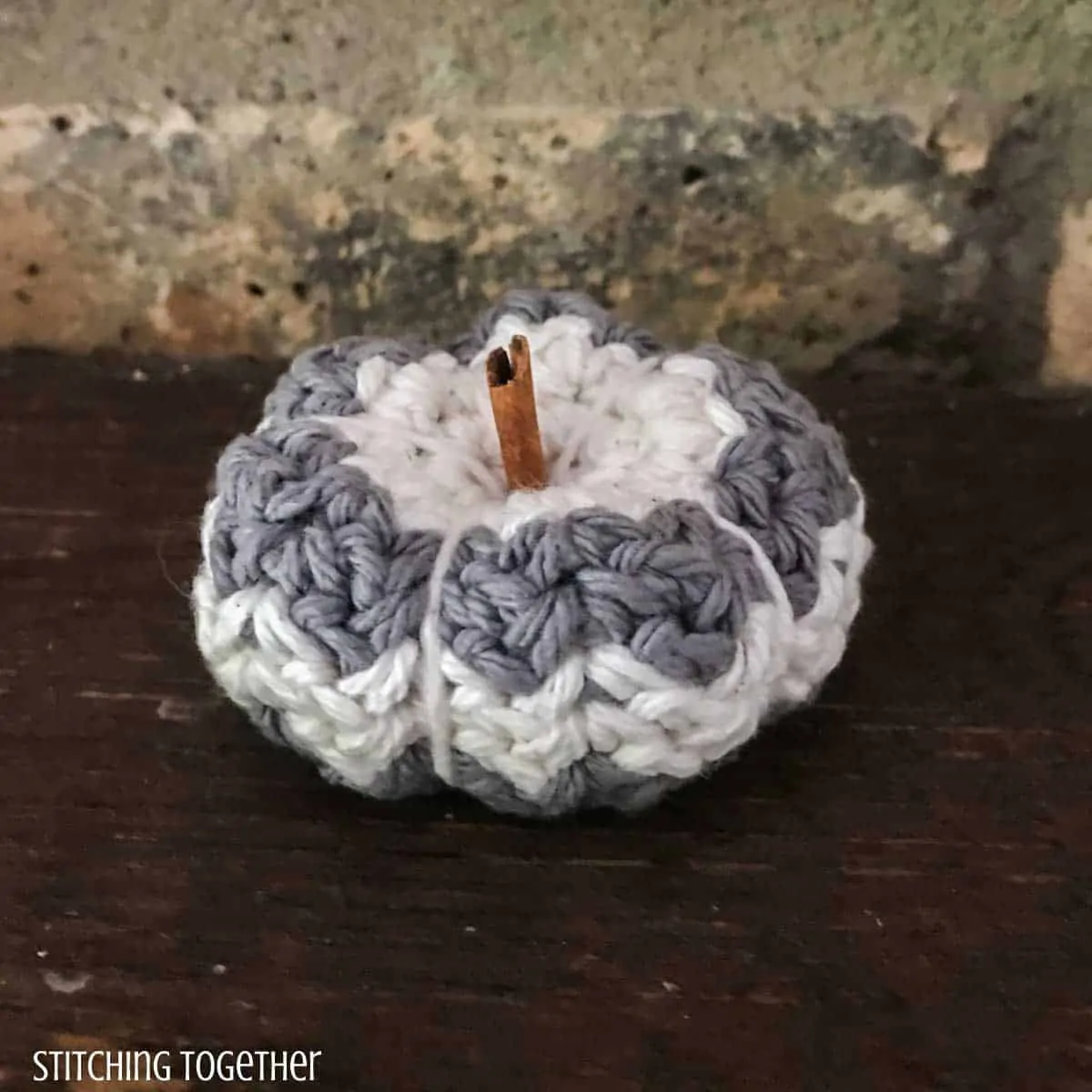 small crochet pumpkin with strips and a cinnamon stick stem