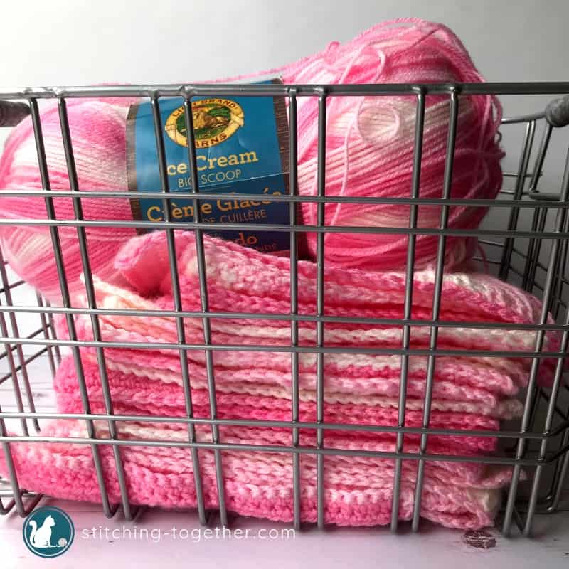 pink crochet squares stack in a basket with yarn on top