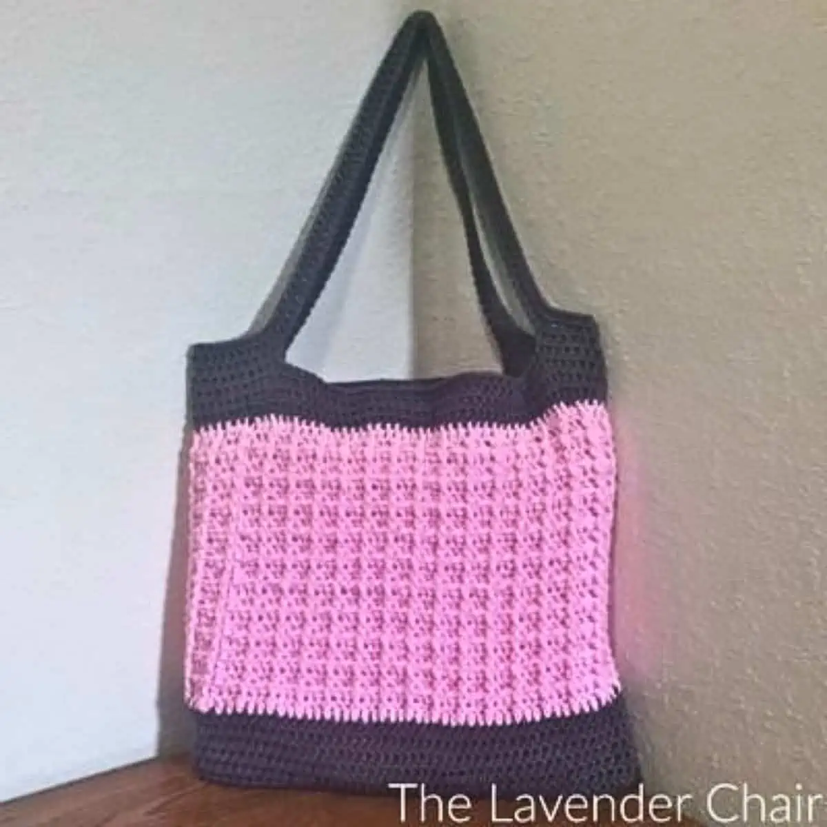 pink and brown crochet bag sitting on a chair