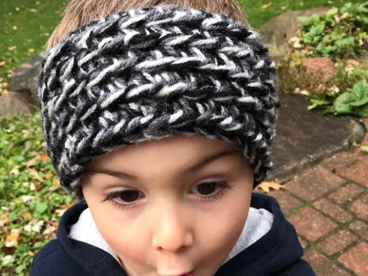 Boy wearing black and gray crochet ear warmer making a funny face