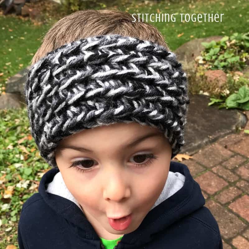 Boy wearing black and gray crochet ear warmer making a funny face