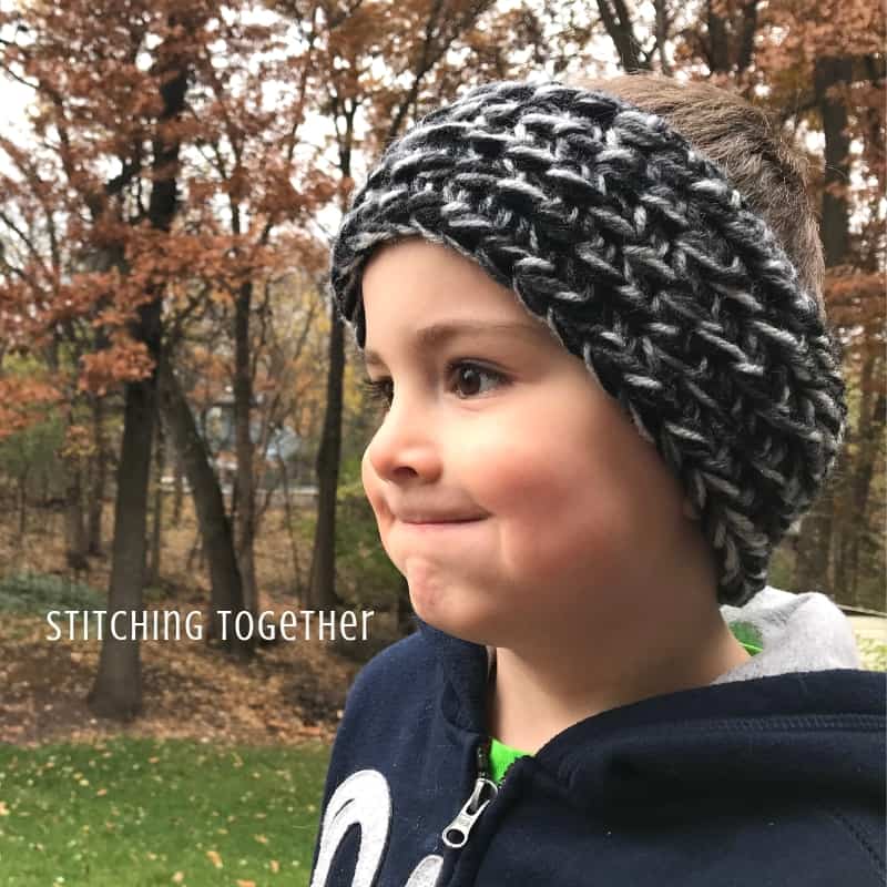 Child wearing a black and gray chunky crochet ear warmer