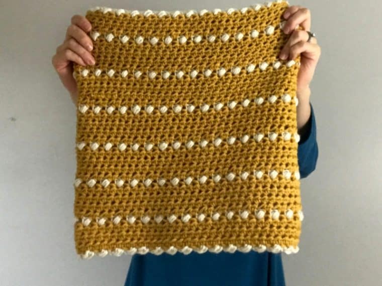 yellow and white crochet cowl being held up