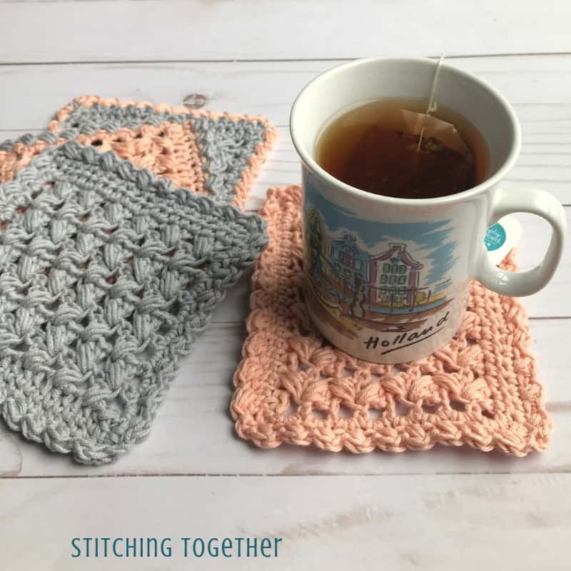 four pink and gray square crochet coasters and a cuppa