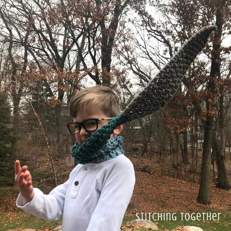 Boy tossing a blue and brown crochet scarf over his shoulder