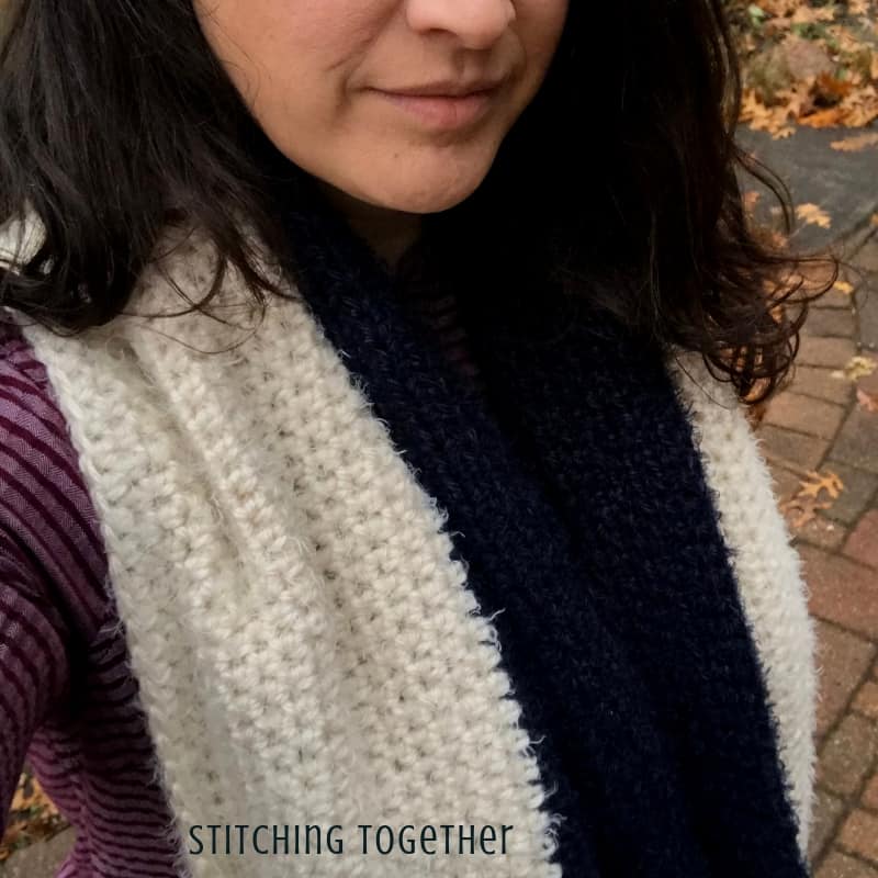 ivory and blue crochet infinity scarf being worn by a lady