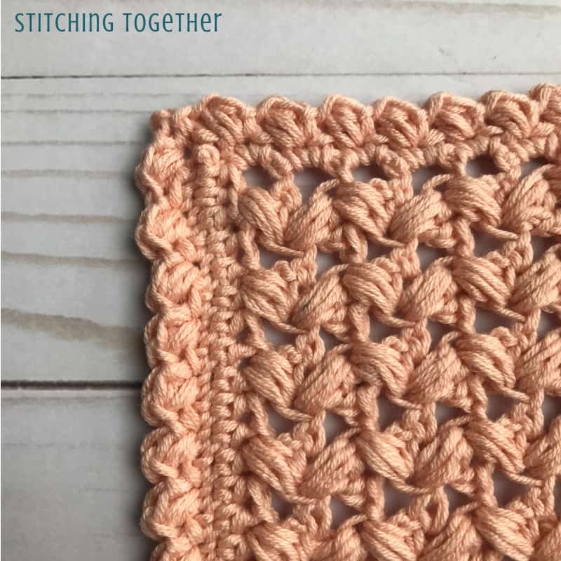 corner of a pink square crochet crochet coaster with zig zag puff stitches