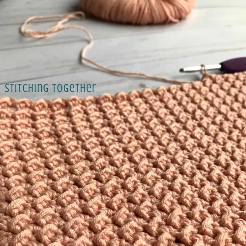 yarn and pink crochet fabric with hook