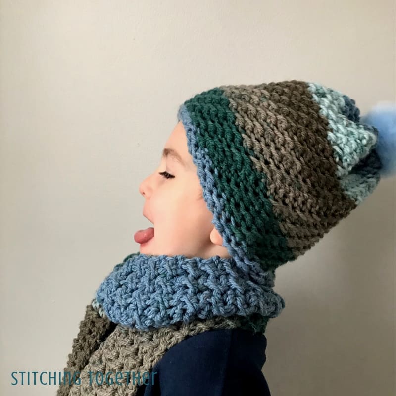 boy wearing crochet hat and scarf with his tongue out
