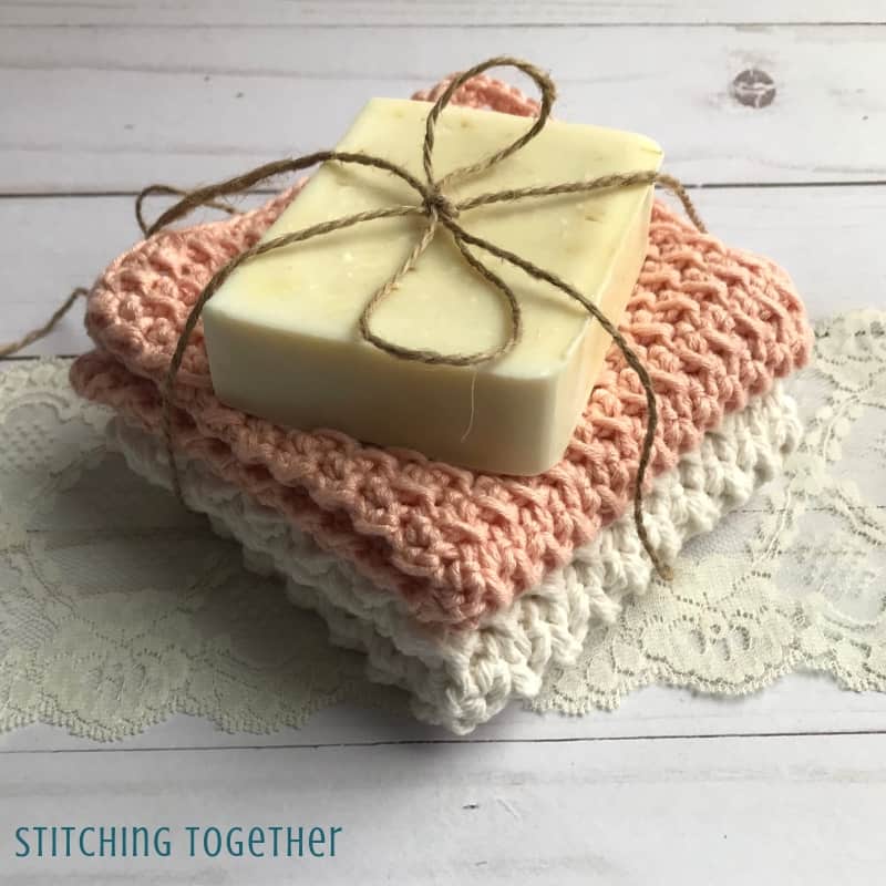 two crochet washcloths stacked with soap and tied with jute
