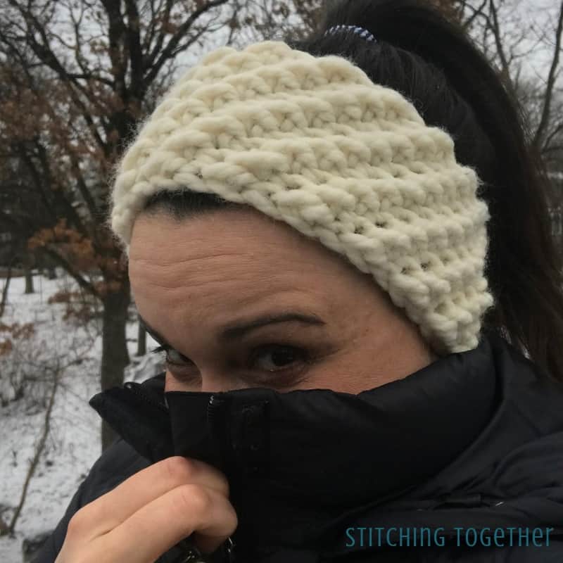 cold lady with off white warm crochet headband and black coat