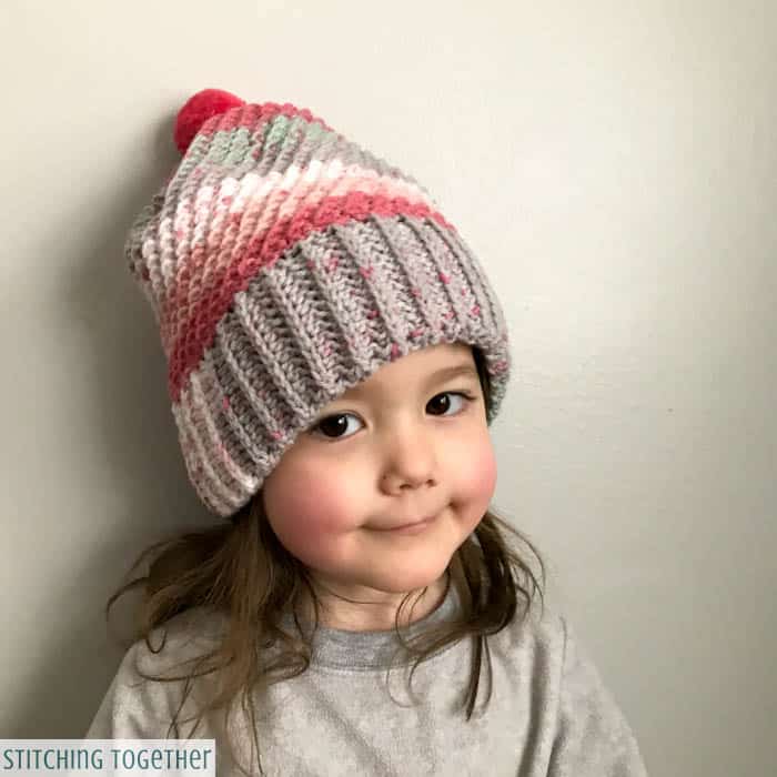 little girl wearing a gray and pink crochet hat
