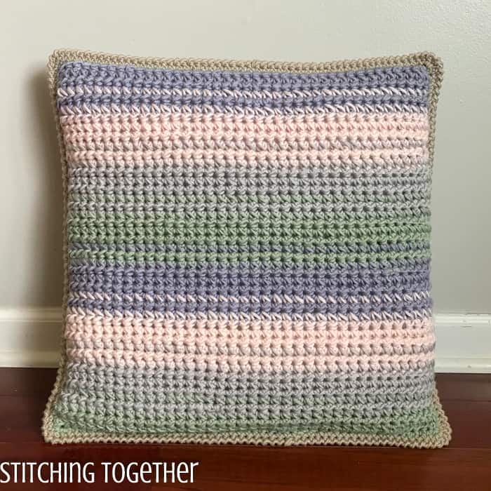 striped crochet throw pillow sitting on floor