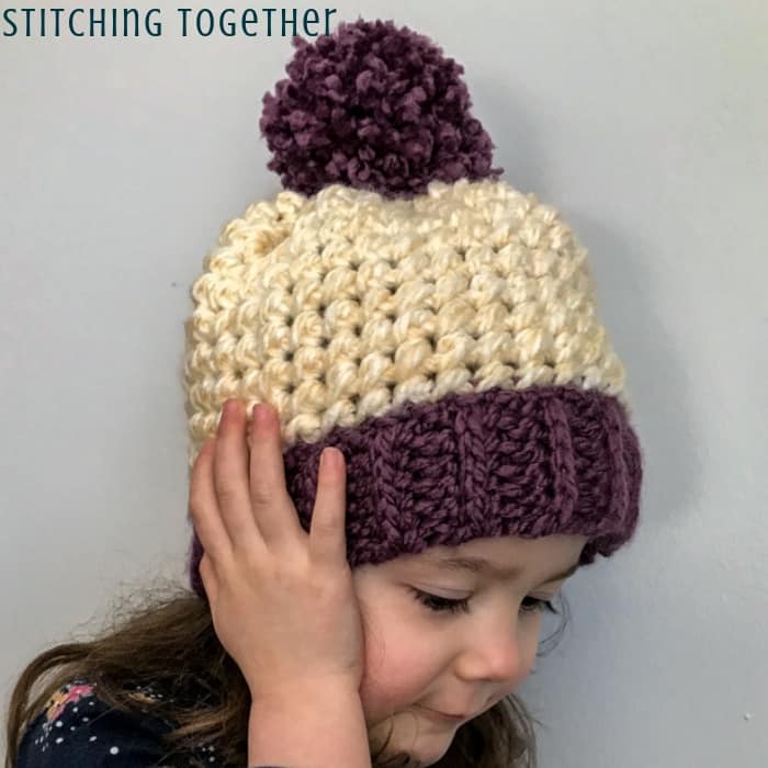 Kid in chunky crochet hat with pom pom