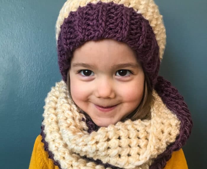 girl wearing purple and white crochet scarf and hat