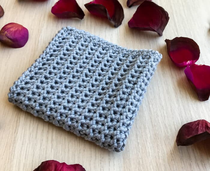 gray crochet washcloth surrounded by rose petals
