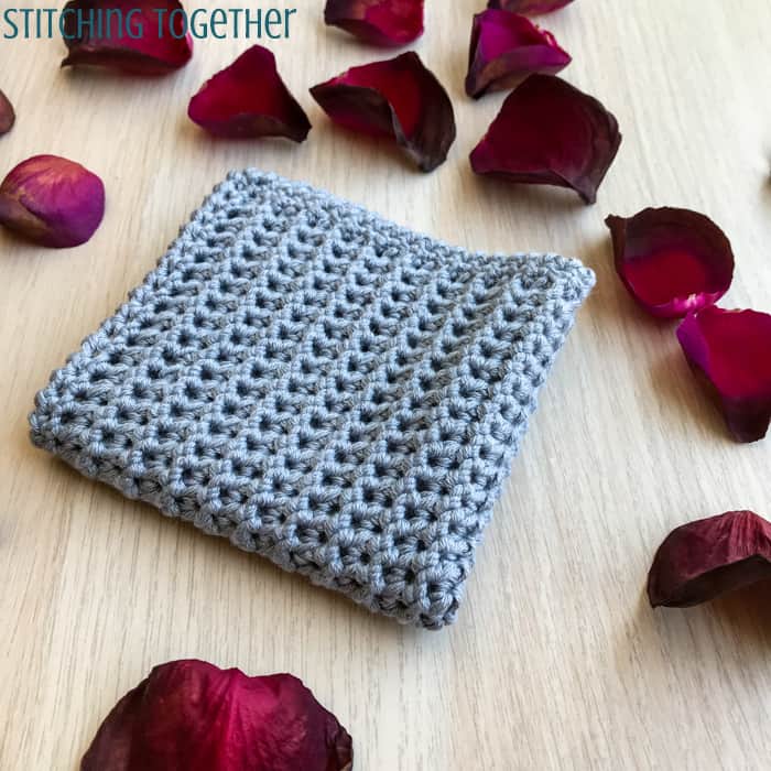 gray crochet washcloth surrounded by rose petals 