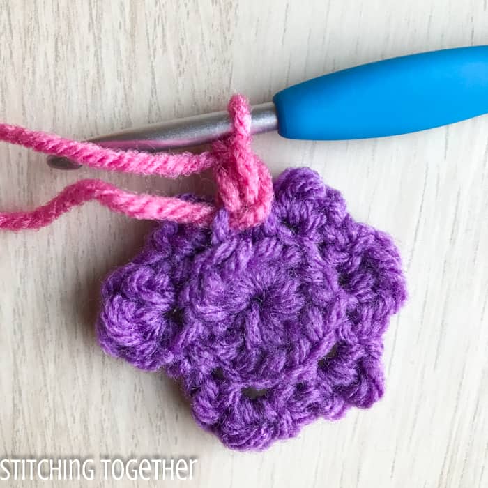 adding pink yarn to the back of a crochet flower