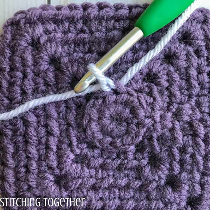 adding white yarn to a purple crochet square