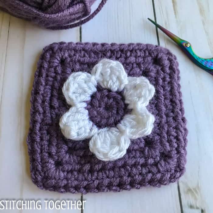 crochet flower granny square with a white flower and purple square