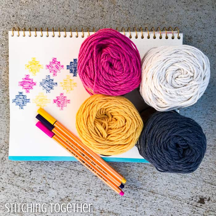 four balls of yarn, matching pens and a design drawn on graph paper