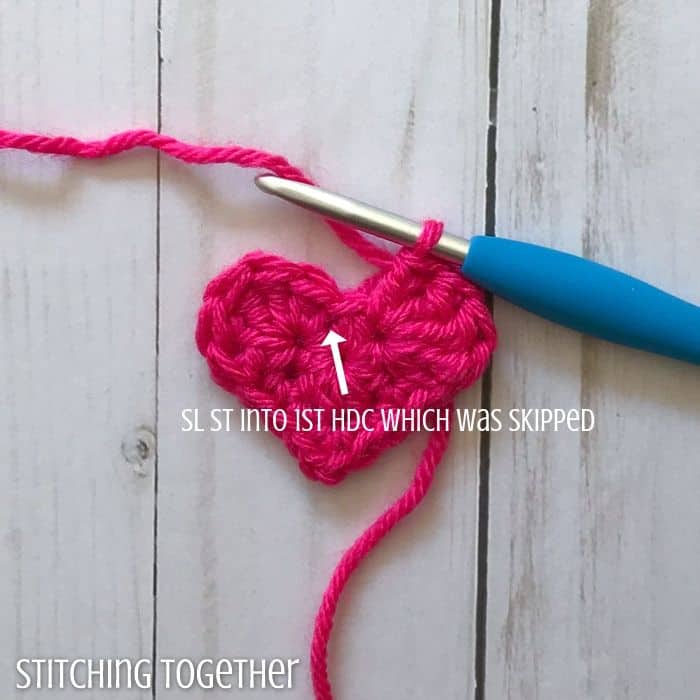 partially finished heart with an arrow showing where to put the next crochet stitch