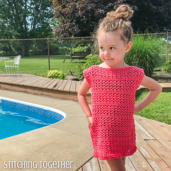 little girl wearing a pink crochet dress by a pool