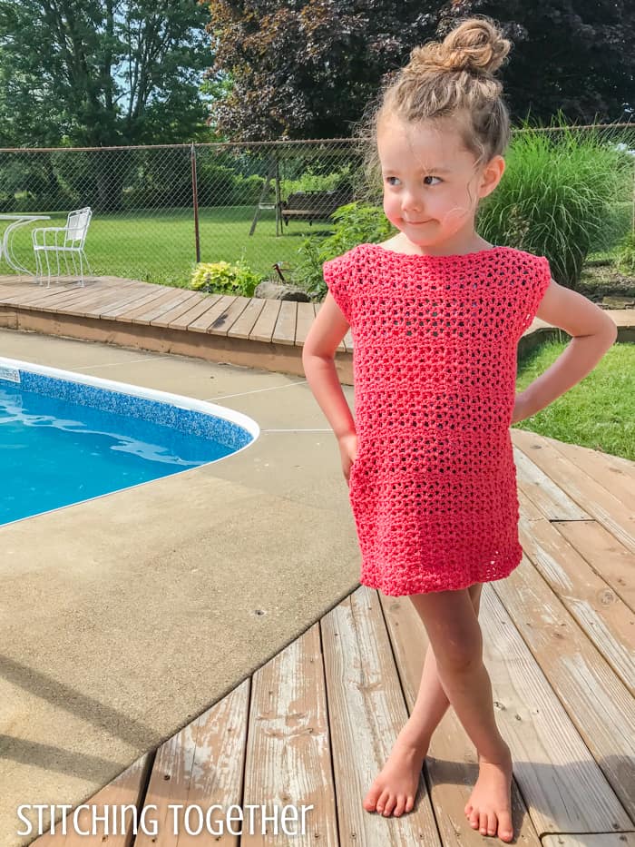 child wearing a pink crochet girl dress while standing by a pool